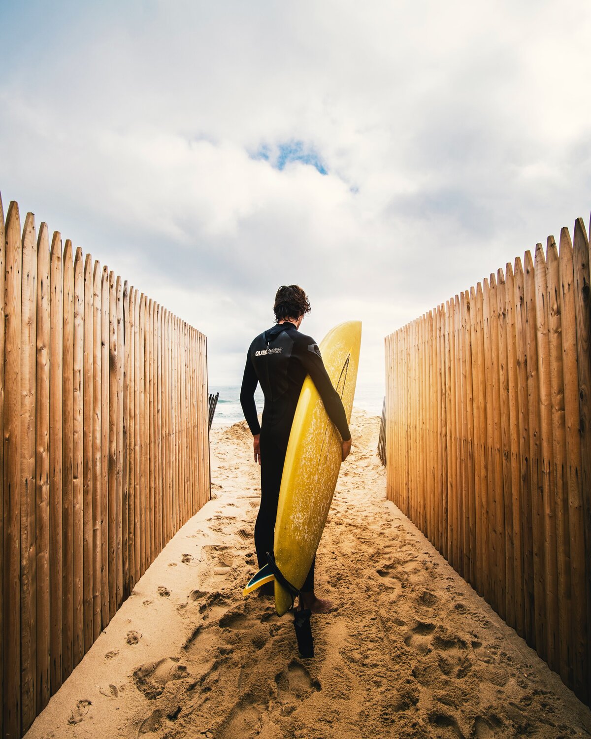 Surfer walking between fences