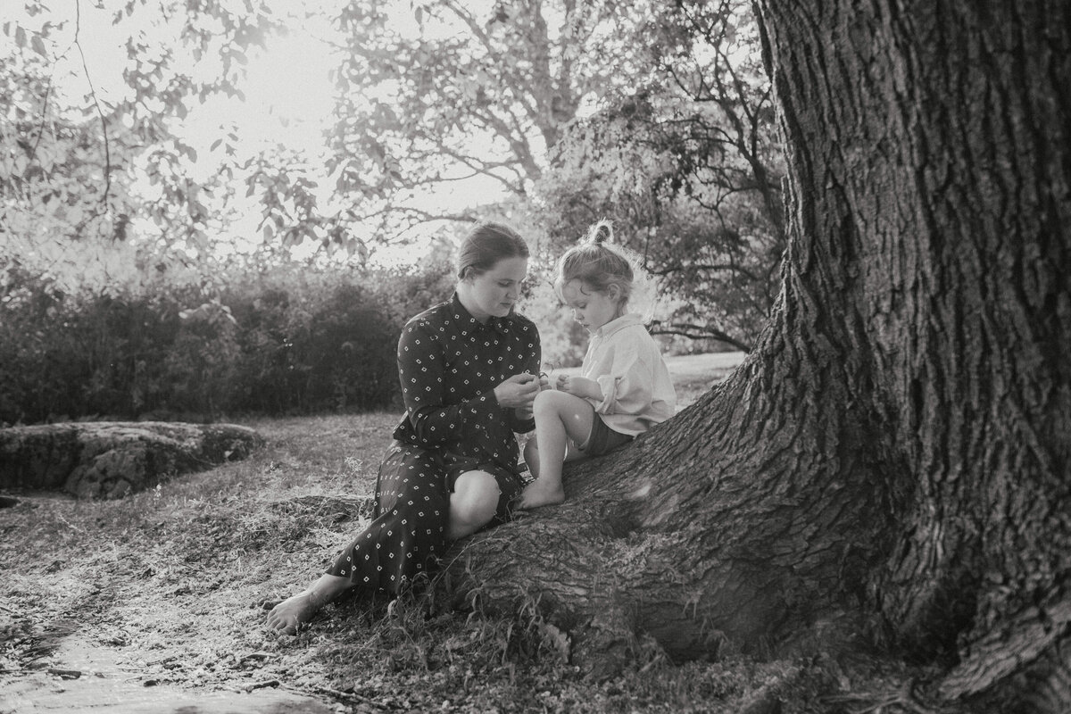 Family photograph of mother and her 3-year old son sitting on a tree in Helsinki in Finland