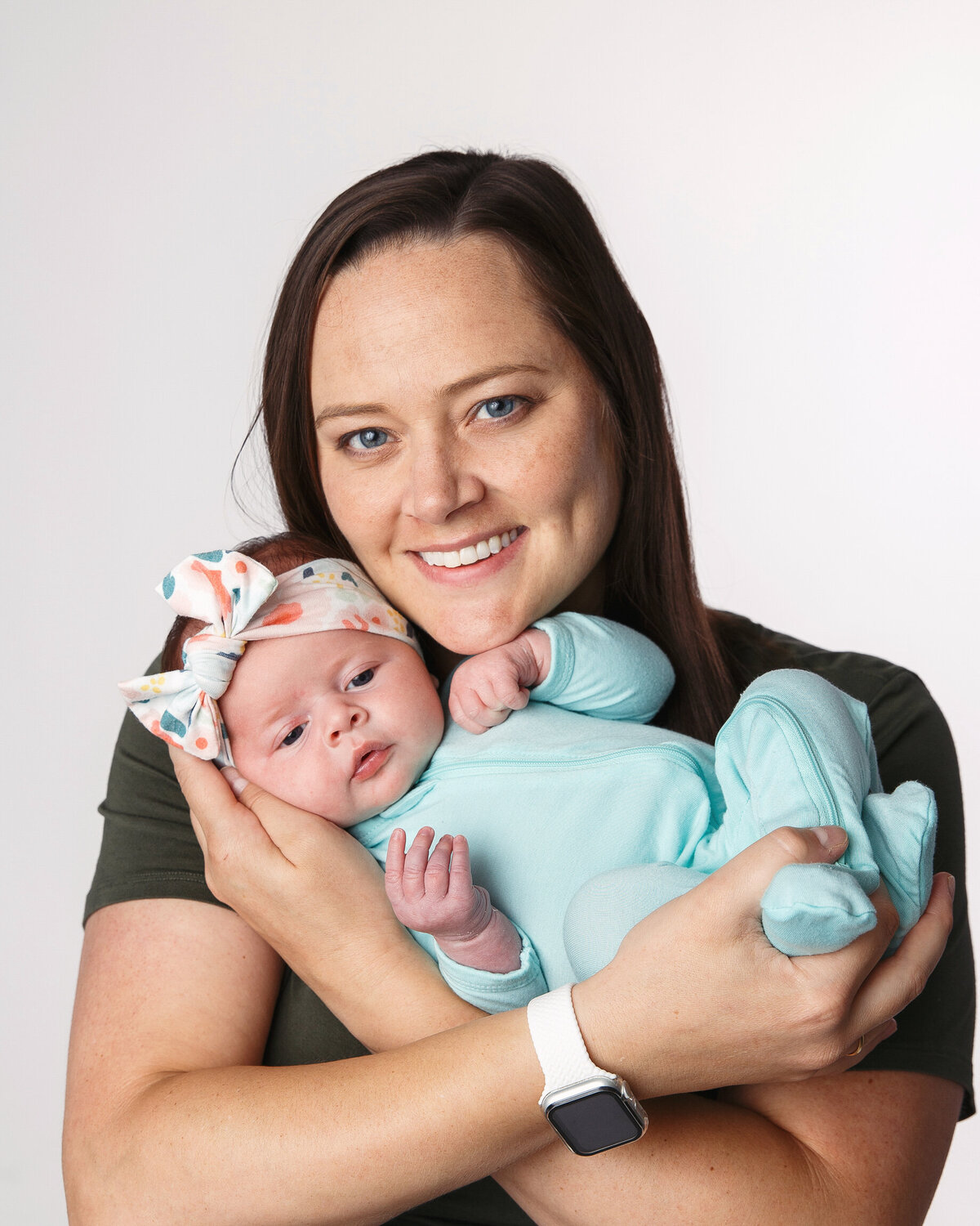Mom holding her newborn baby girl posed on a white background