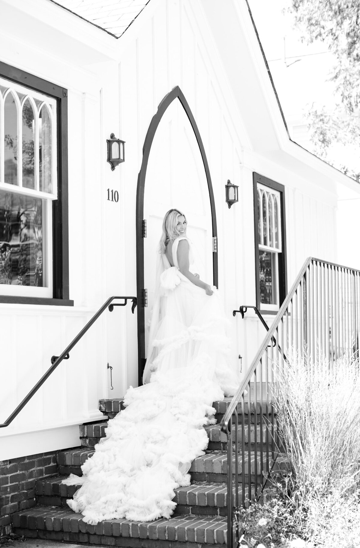 Bride wearing a flowy dress with a long train on a doorsteps of a historic chapel in Raleigh, NC. All Saints Chapel wedding photographer.