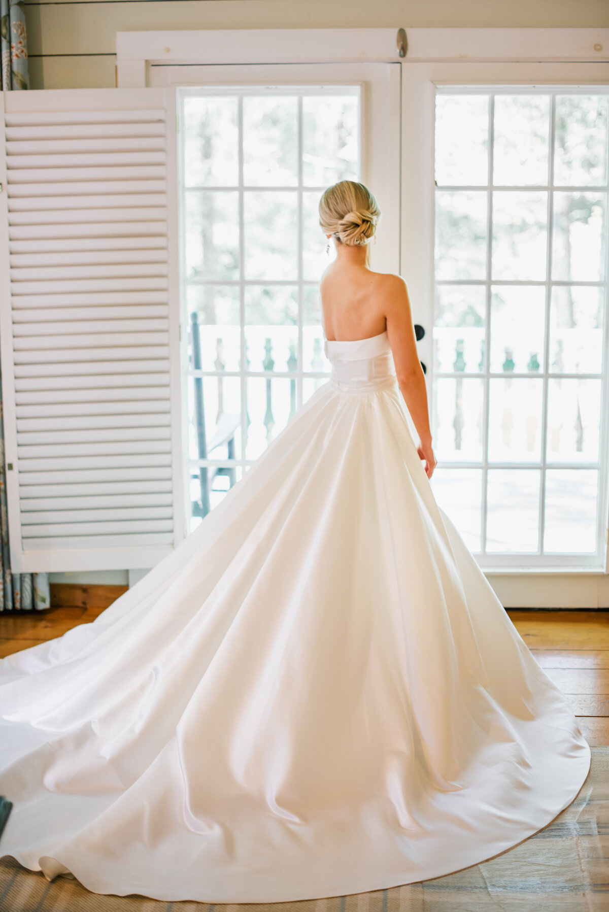 Bride in elegant classic ballgown standing near French doors at Old Edwards Inn wedding in Highlands, NC.