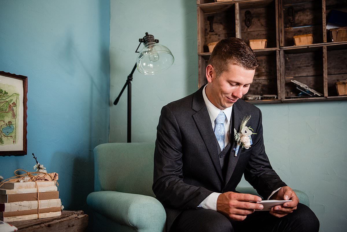 Groom smiling candidly while reading a note from his soon to be wife