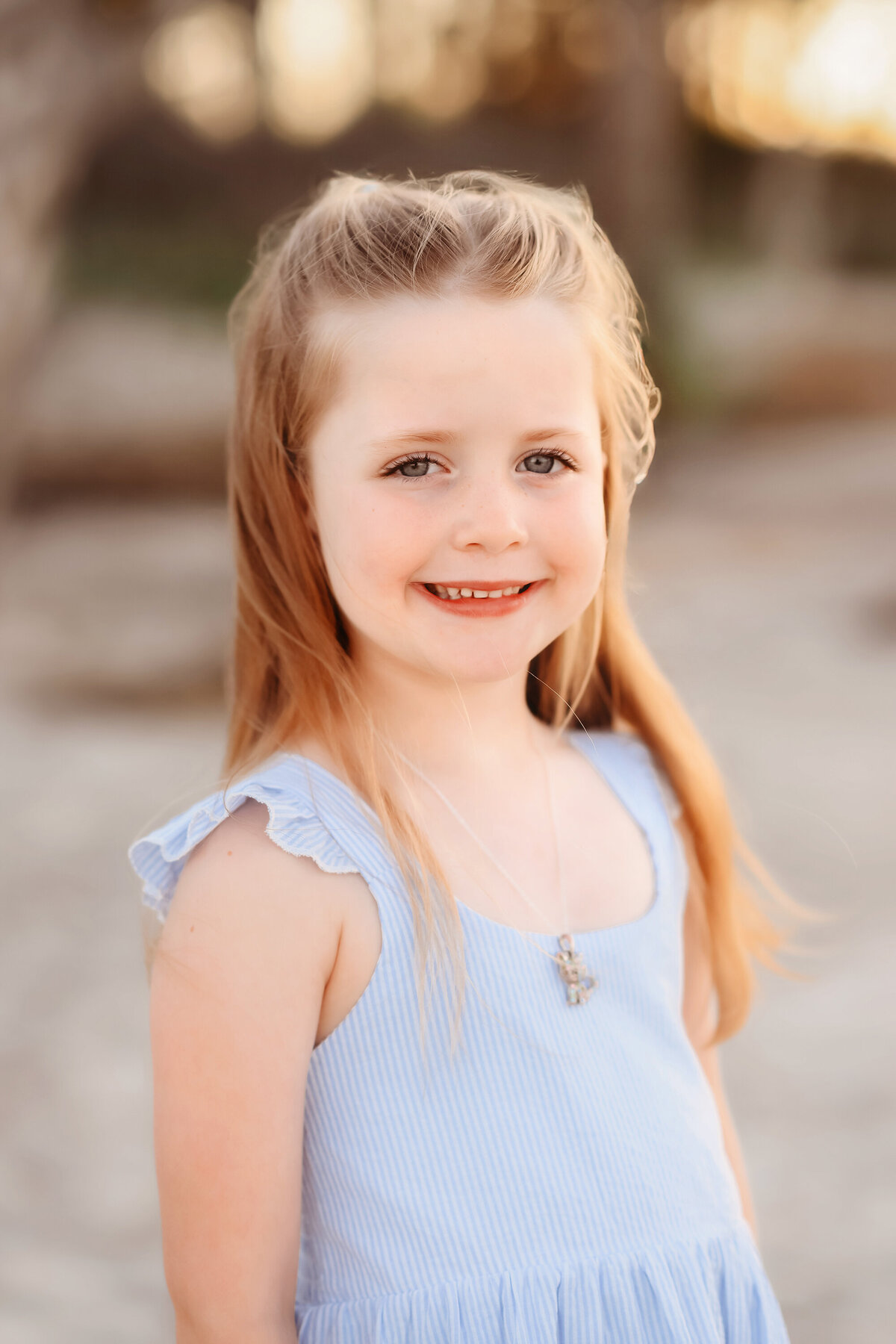 Little girl smiles into the camera during Family Pictures on Folly Beach. 
