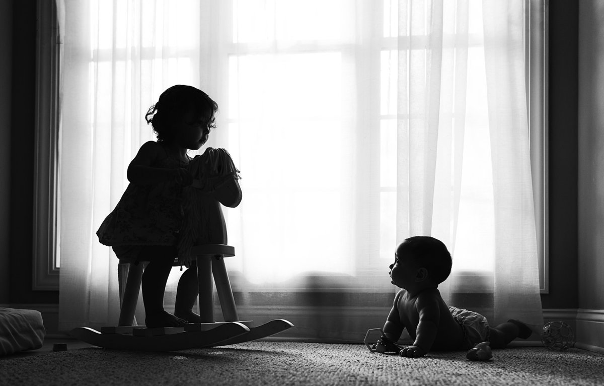 charlotte documentary photographer jamie lucido captures a beautiful silhouette of children at play in a playroom next to a large window
