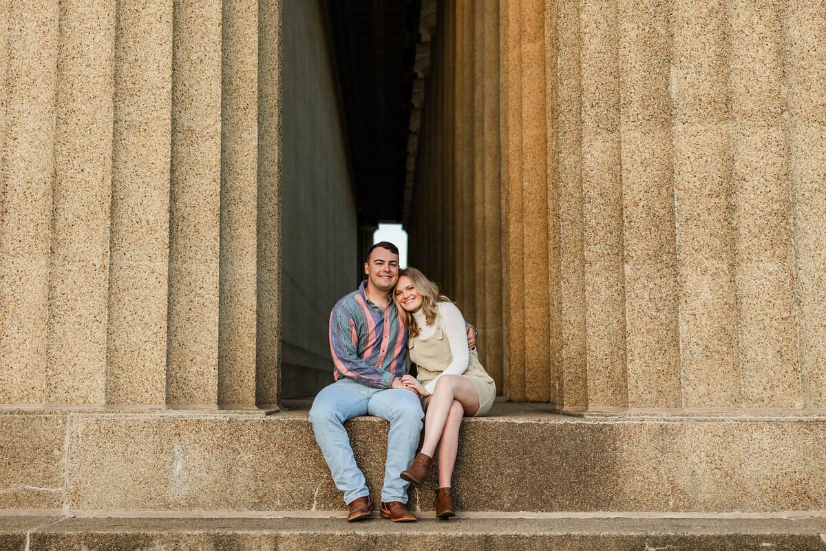 Couple sitting on large steps next to massive pillars