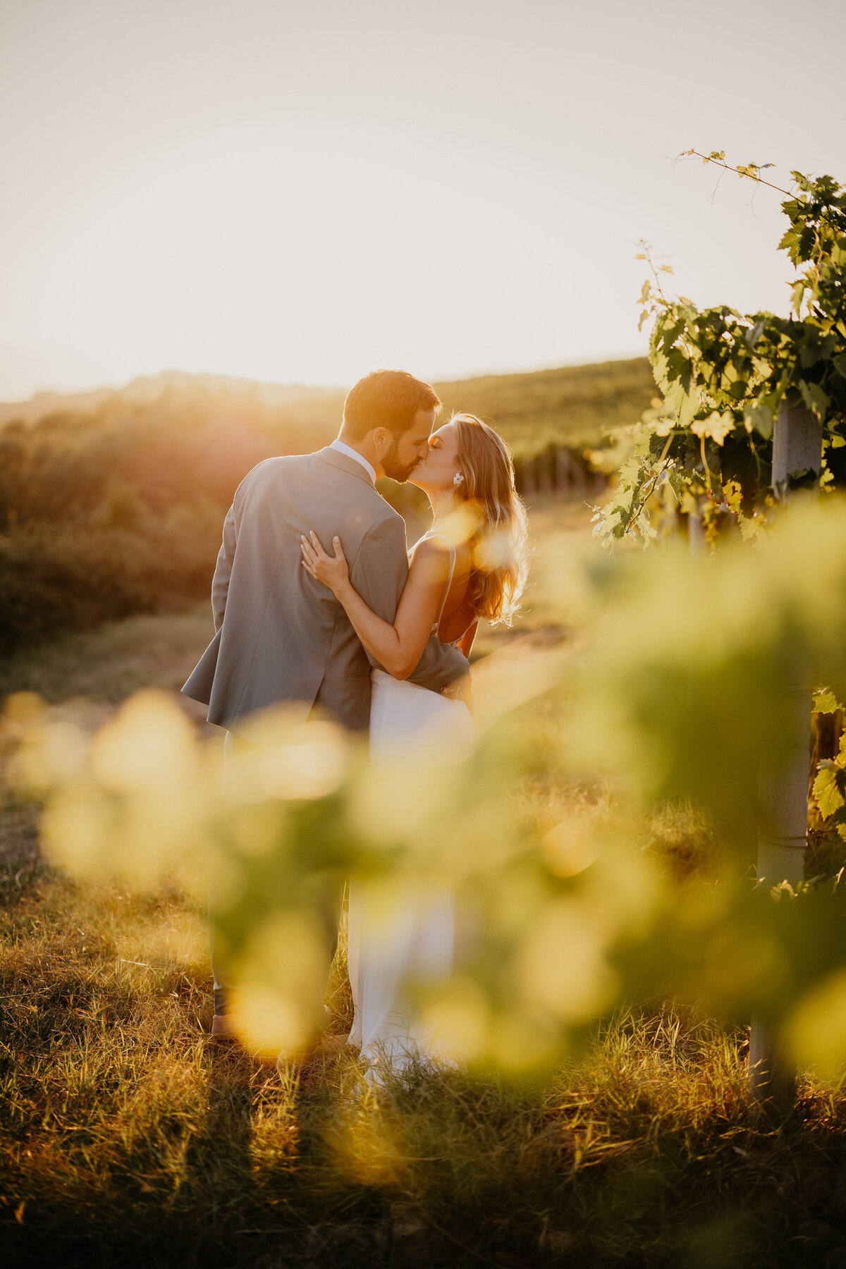Bride and groom kissing in the vineyards at sunset at Borgo Divino, Tuscany wedding photographer.