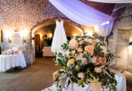 A bouquet of flowers sitting on top of a table, with the brides wedding dress hanging in the background