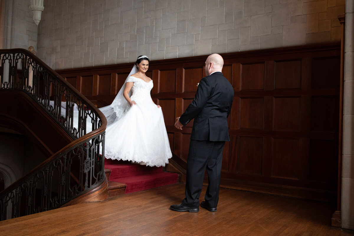 bride-walking-down-grand-staircase-groom-first-look