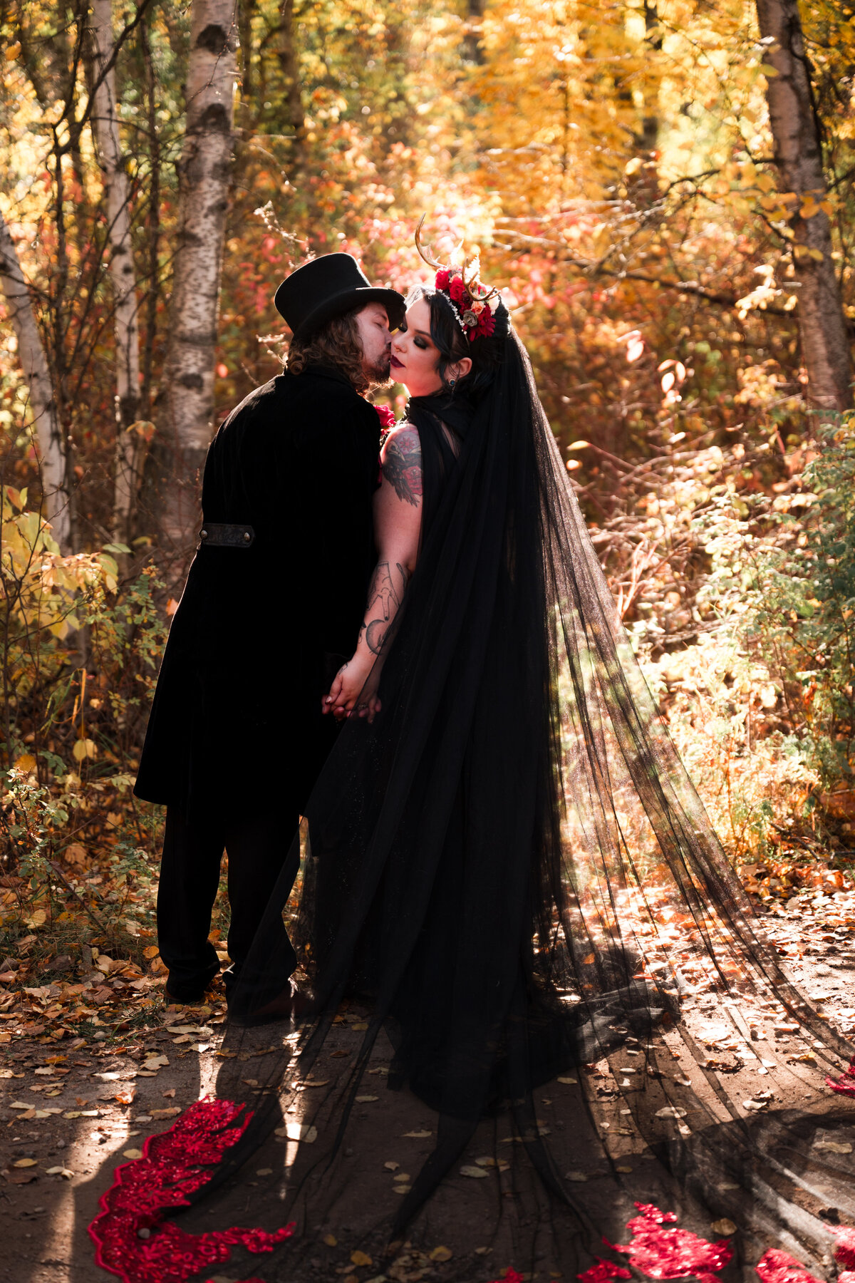 goth bride and groom kiss, bride is in a black dress with a black veil