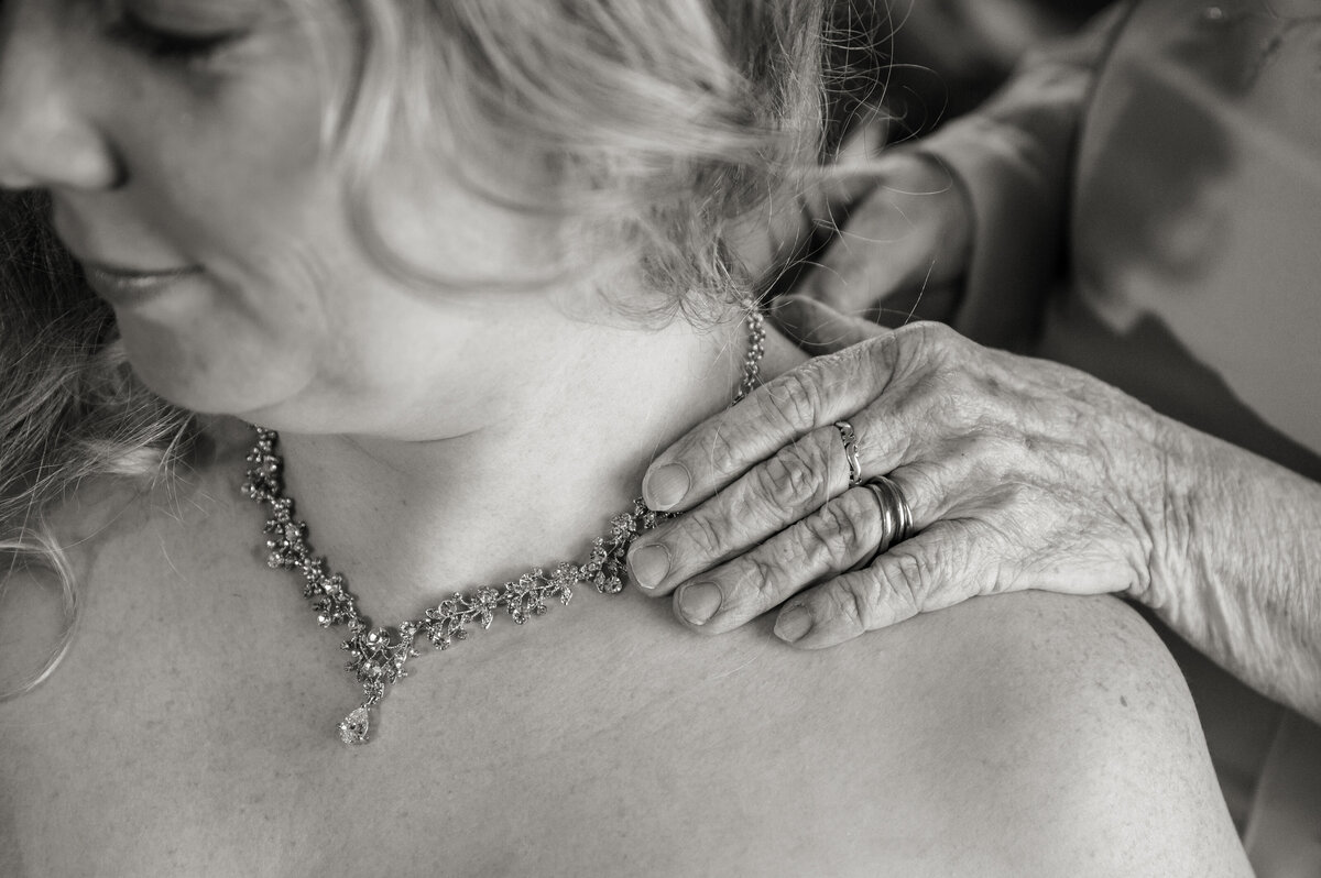 Brides mothers hand putting on jewelry.