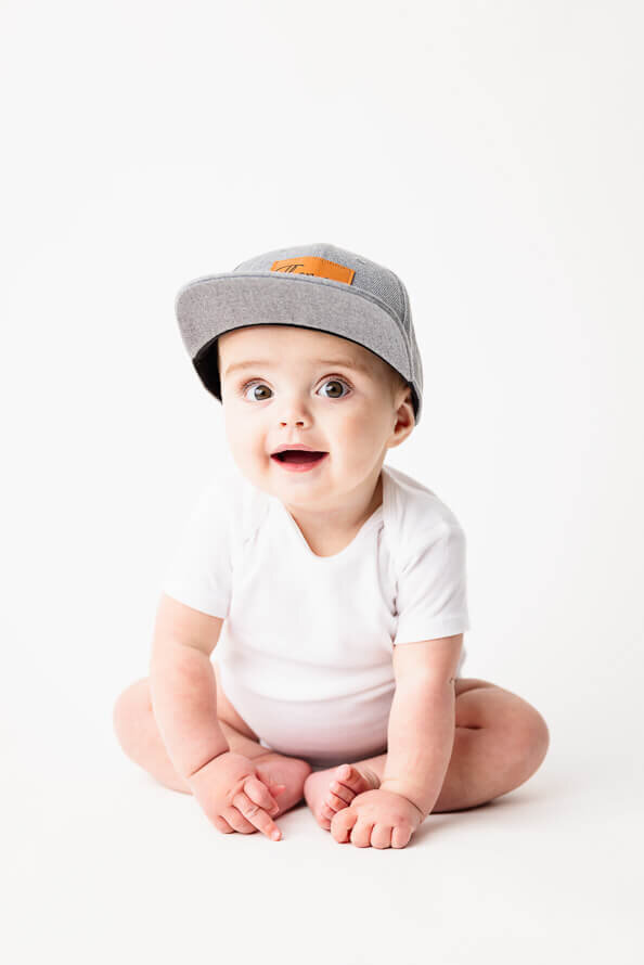 One year old boy sits in a white studio.