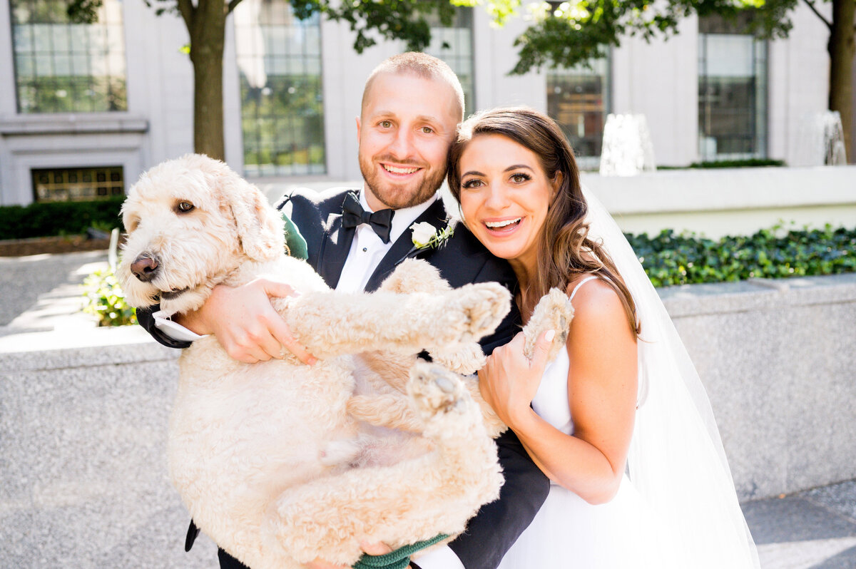 wedding couple smiling for photo with their dog