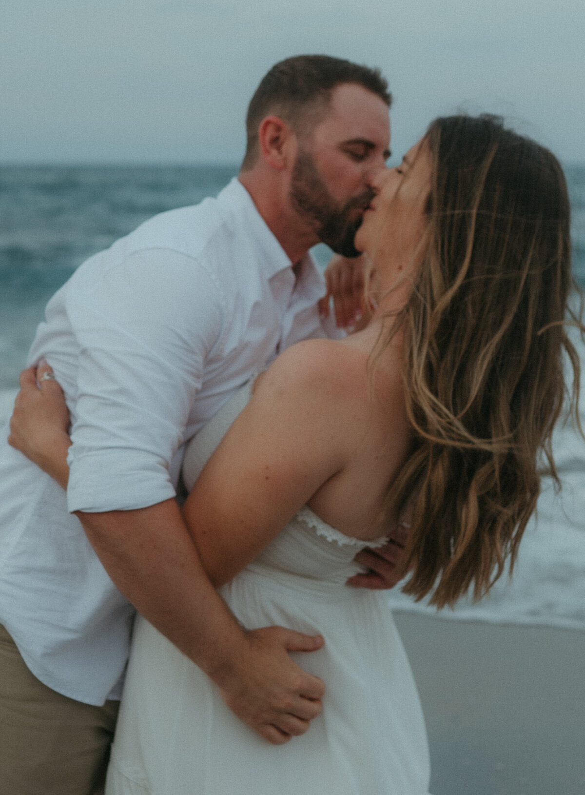 couple kissing on beach during engagement session