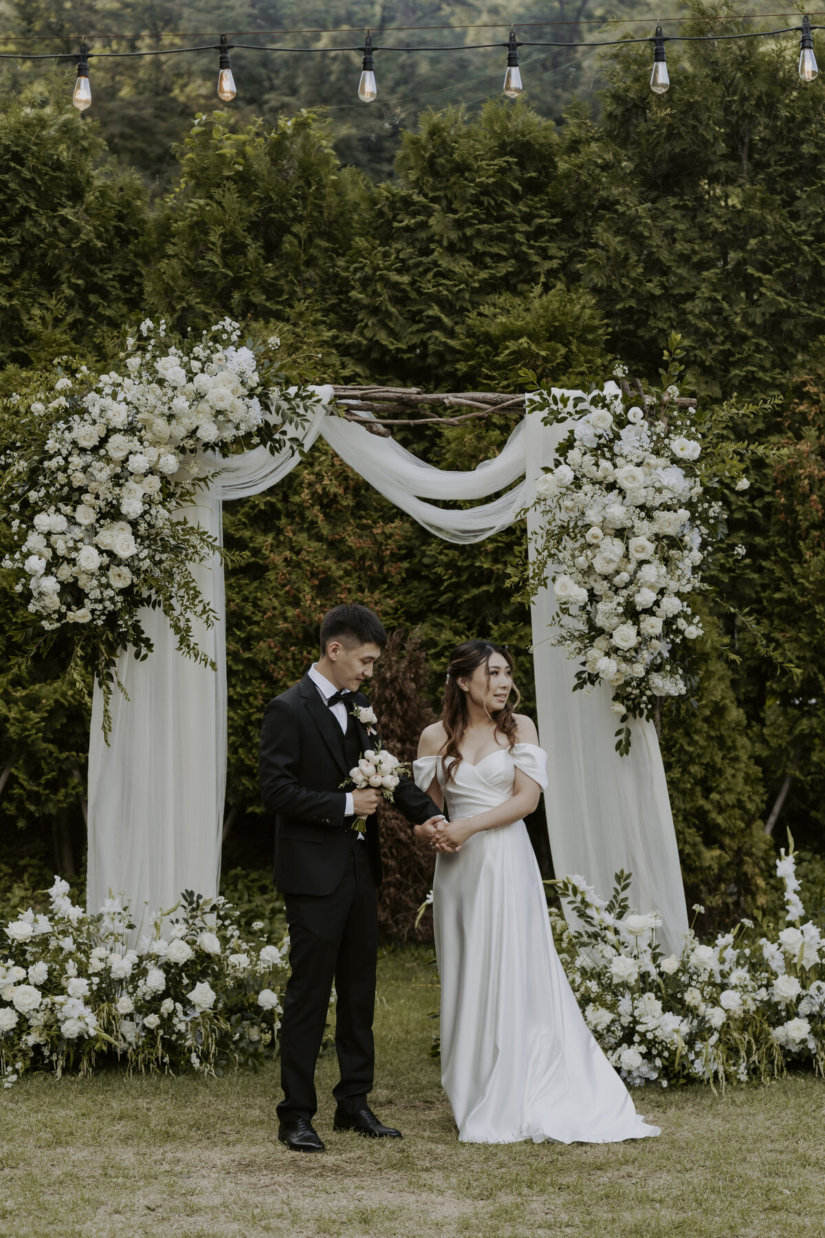 the couple standing while the groom holds the bride's bouquet