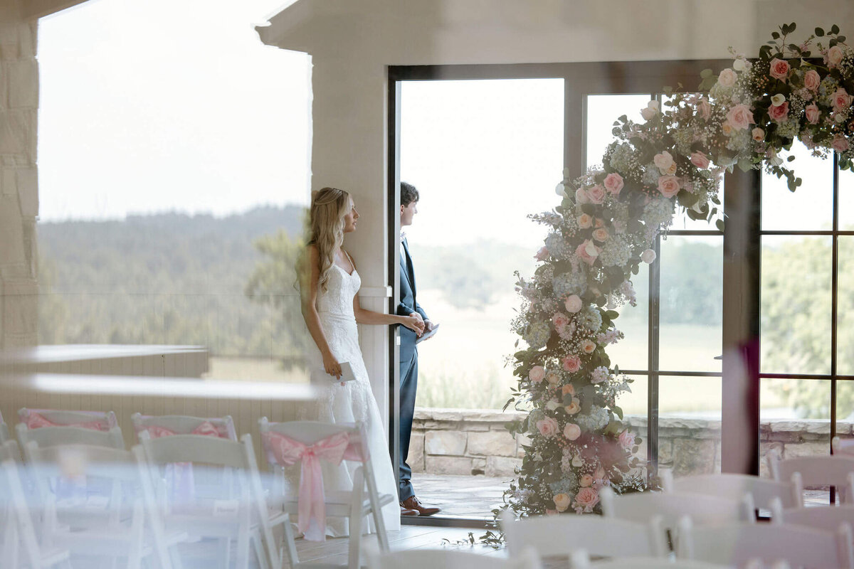 private vows and 1st touch ceremony between bride and groom photographed through wedding chapel window