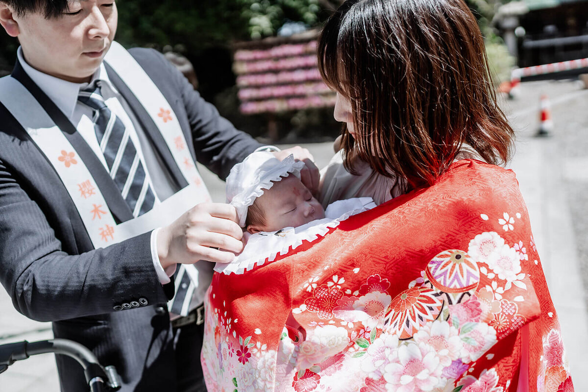 お宮参りで赤ちゃんに帽子を被せるシーン
