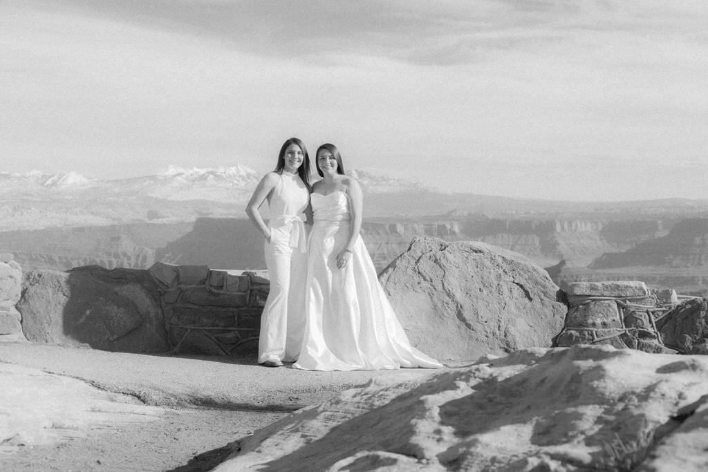 A newlywed couple standing on the edge of a canyon.