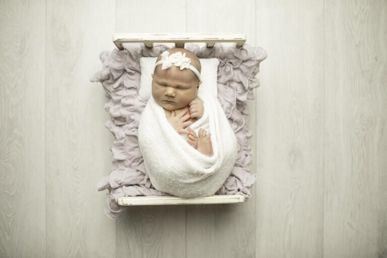 Newborn baby girl peacefully resting on a soft bed adorned with delicate ruffles, creating a dreamy and elegant portrait