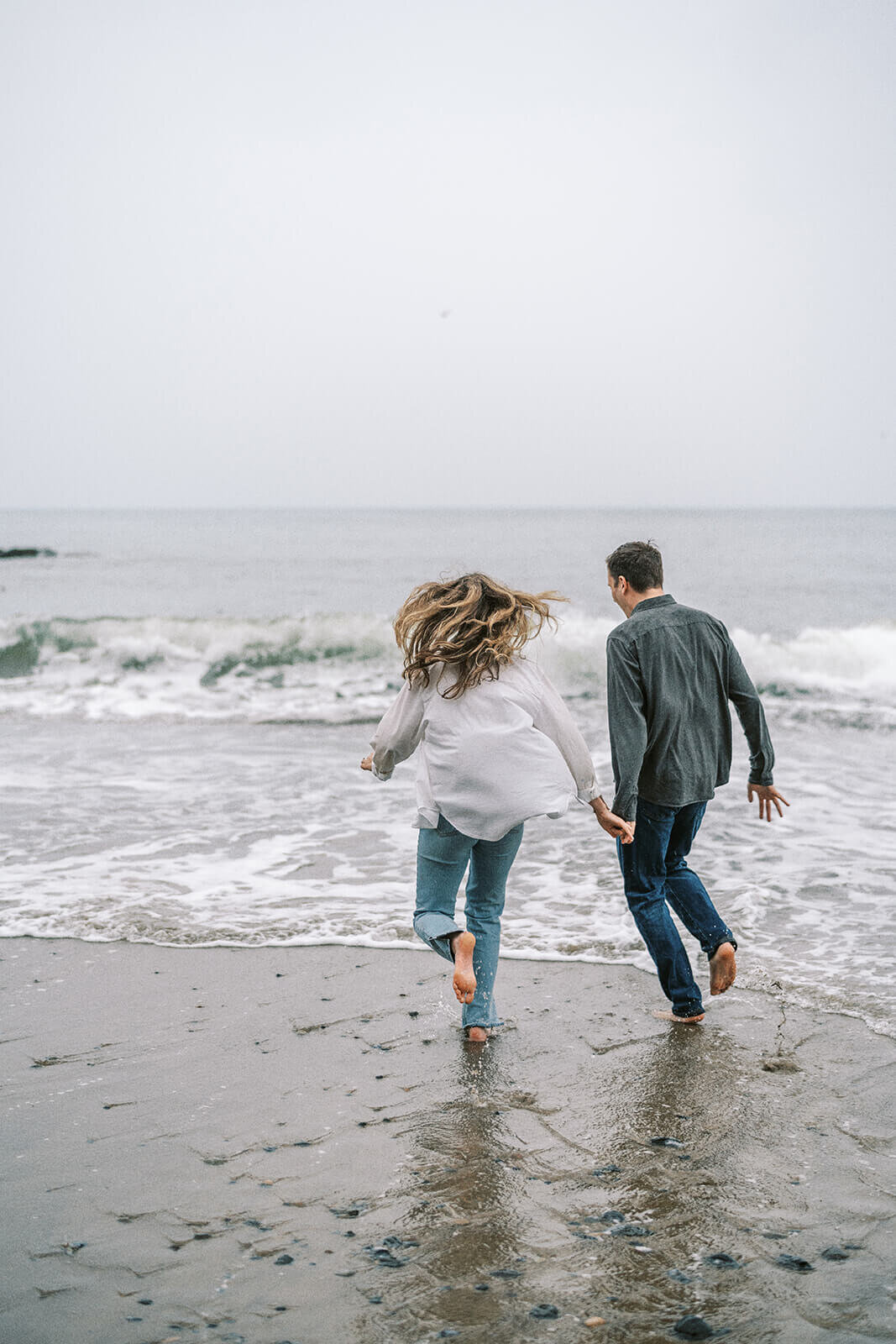 Blurry capture of a couple running towards the waves.