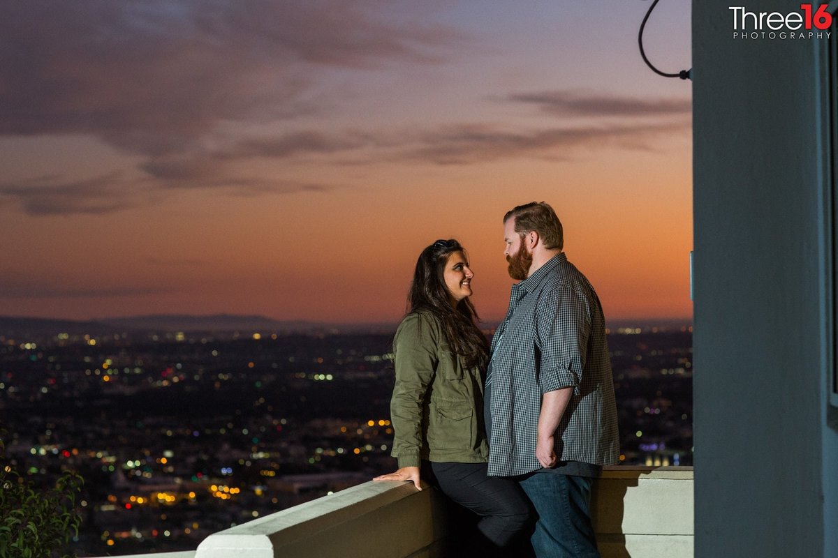 Engaged couple look at each other during a sunset photo session on the balcony of the Griffith Observatory in LA