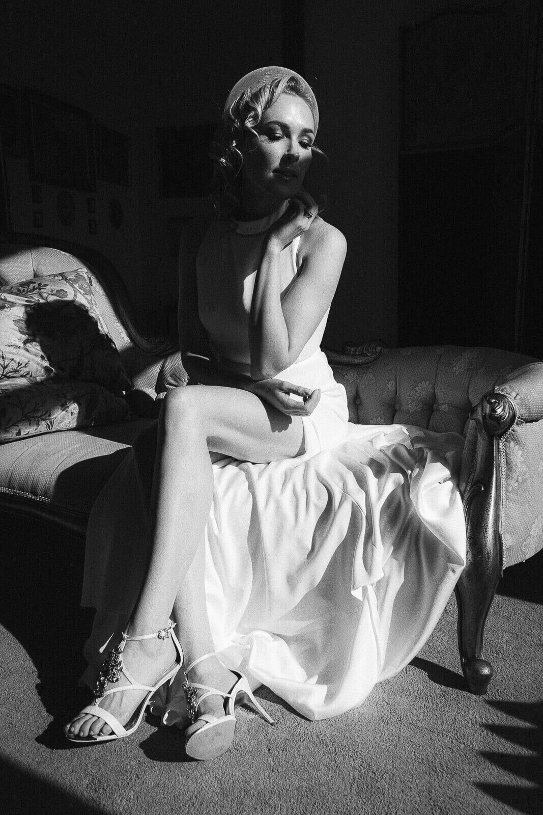 A Cinematic wedding photo of a bride sat down, warmed by the sun shining through the window.