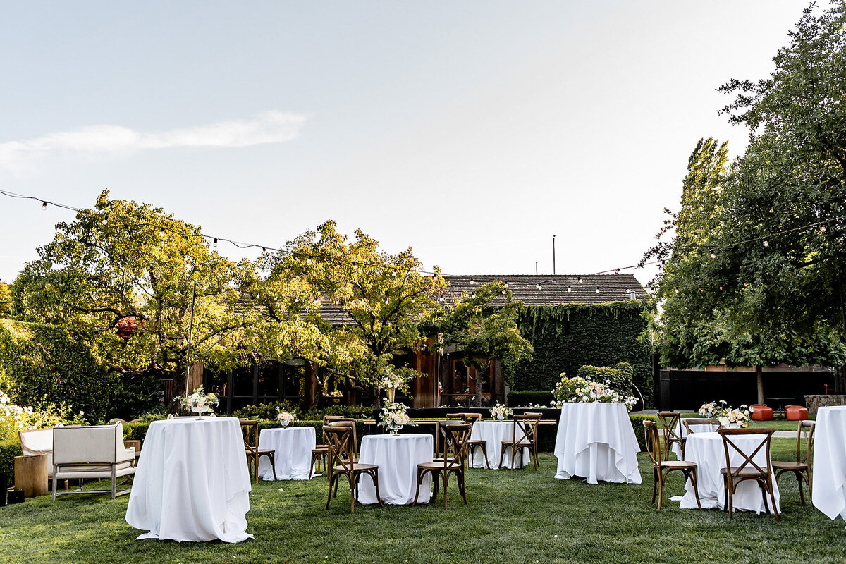 San Francisco Bay Area wedding photographer captures elegant cocktail hour setup with white linens and natural landscaping in daylight at Estate Yountville in Napa Valley