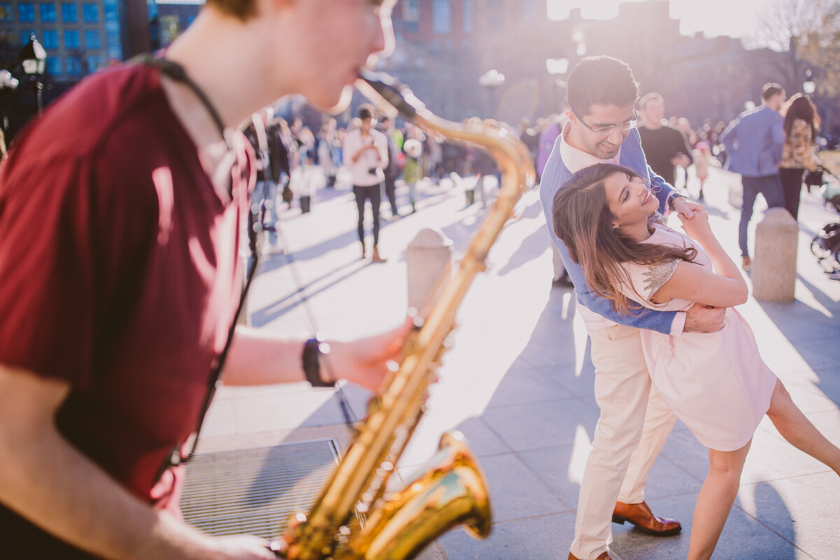 an engaged couple dancing in front of a saxophone player at the washington square park in nyc