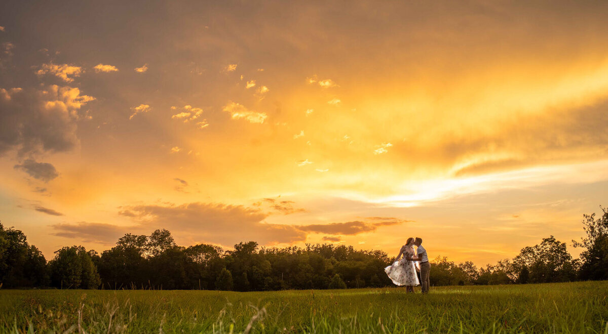Couple embracing at sunset, sky glowing with warm colors
