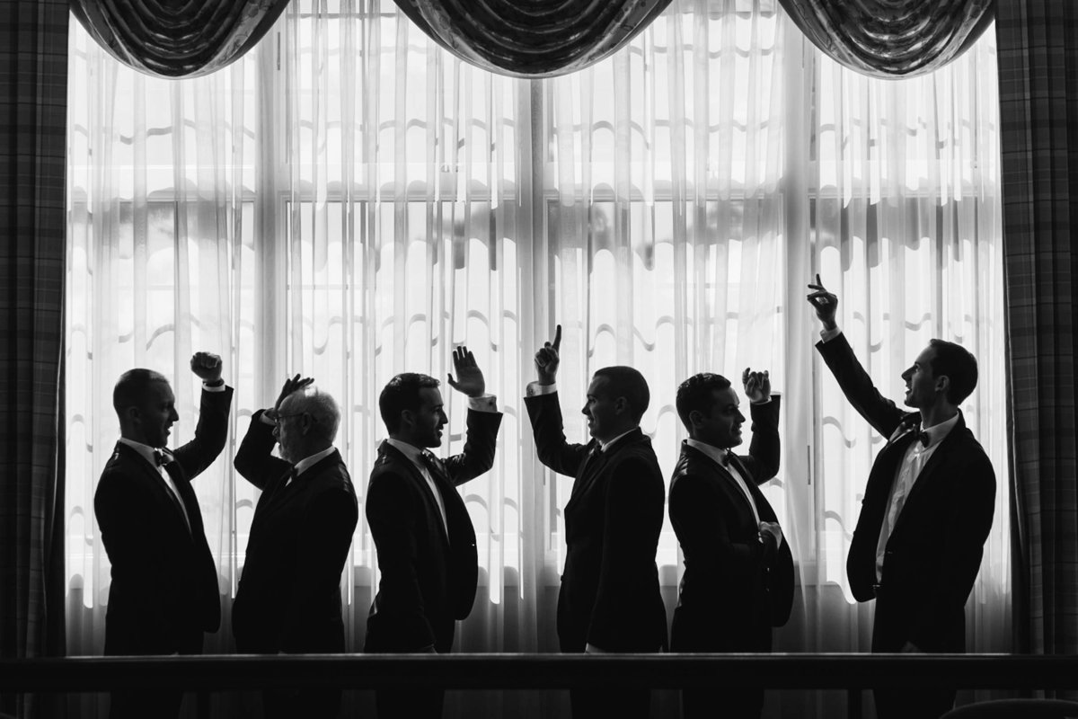 Groomsmen with hands raised in black and white at Stonebridge Country Club