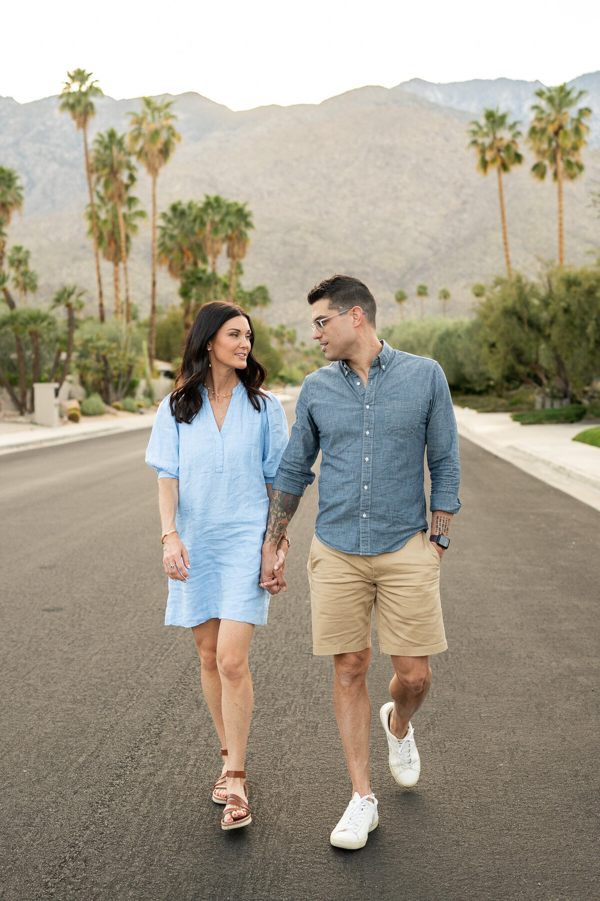 Couple walks while looking at one another during a family photography session in palm springs 