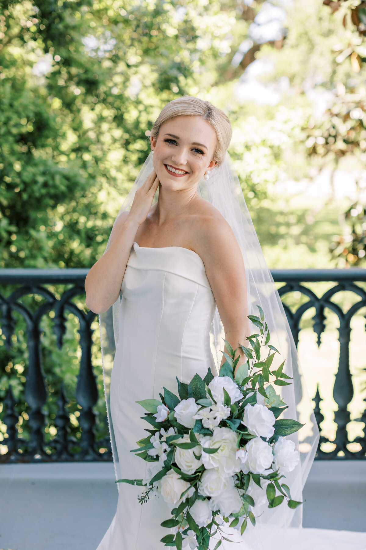 A bride smiles while standing on the porch of Nottoway Plantation in Louisiana.