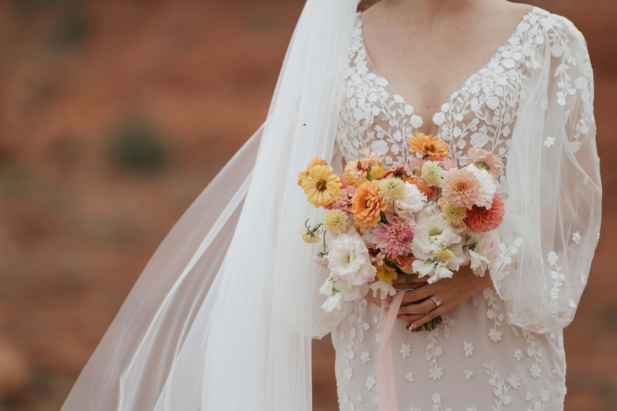 bride holding bridal bouquet against red rock background
