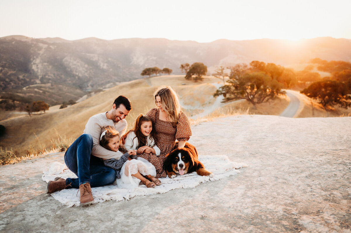 Family and dog snuggling on a blanket with the view of Livermore Del Valle