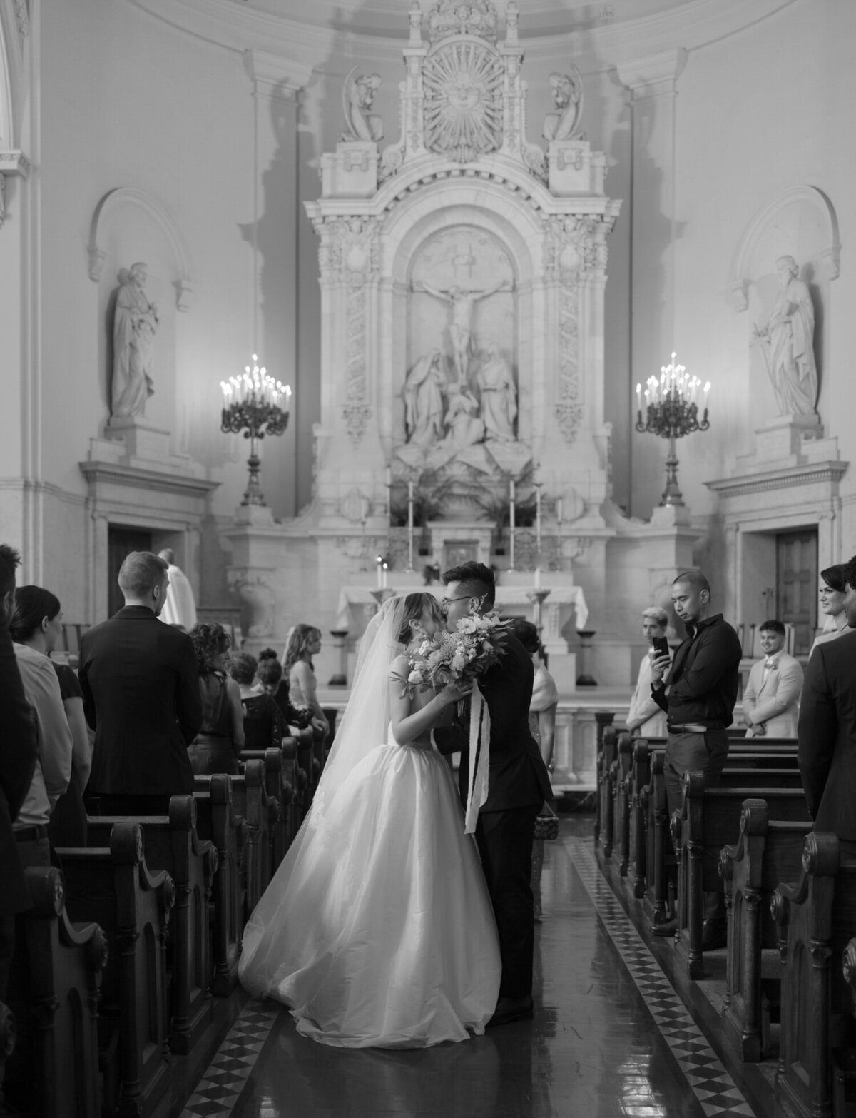 A couple kisses during recessional, wedding ceremony at St. Peter and Paul, Detroit