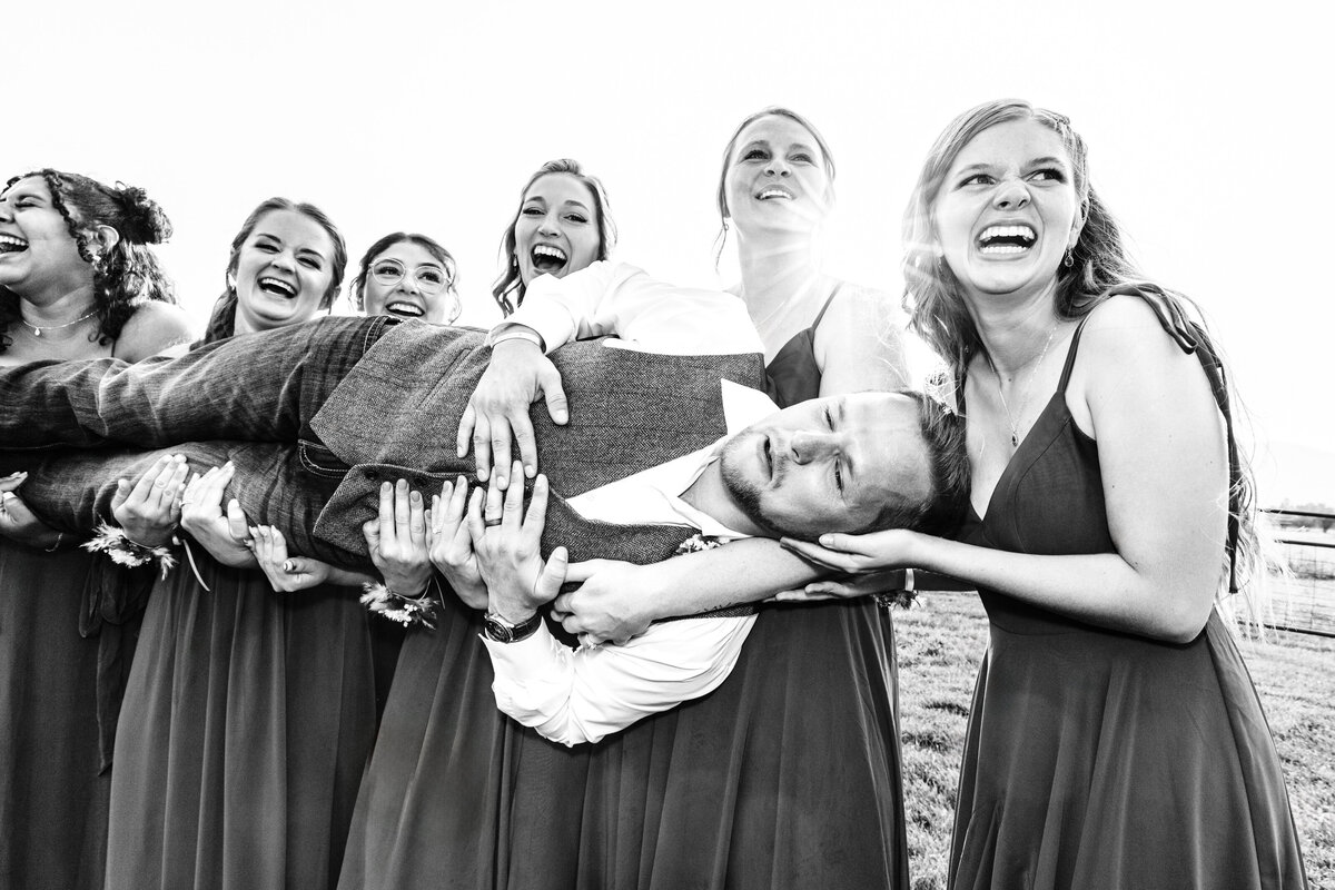 Bridesmaids holding groom up and sideways at Cattle Springs in Arlee, MT