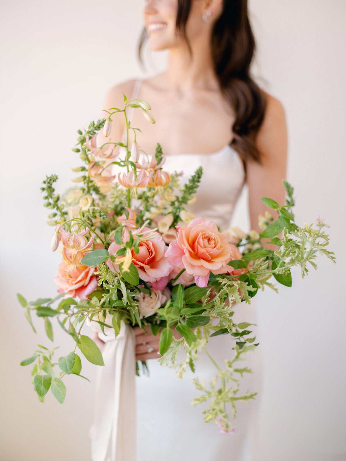 bride smiling holding a gorgeous summer floral bouquet