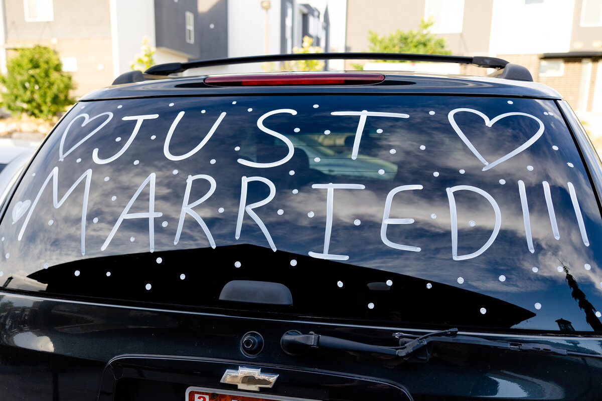 A black SUV with "Just Married" written on the rear windshield in white marker, ready for the couple’s grand exit.