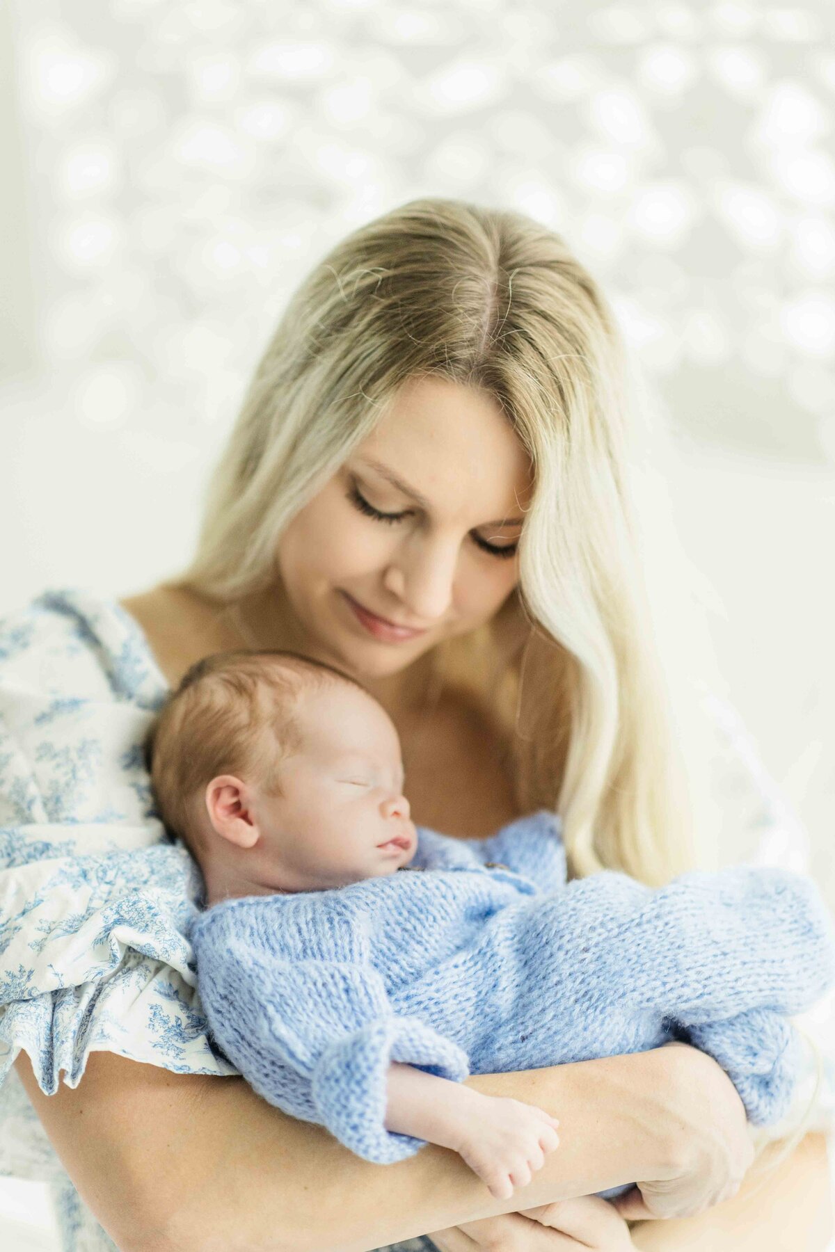 mom glances down towards baby for newborn portrait