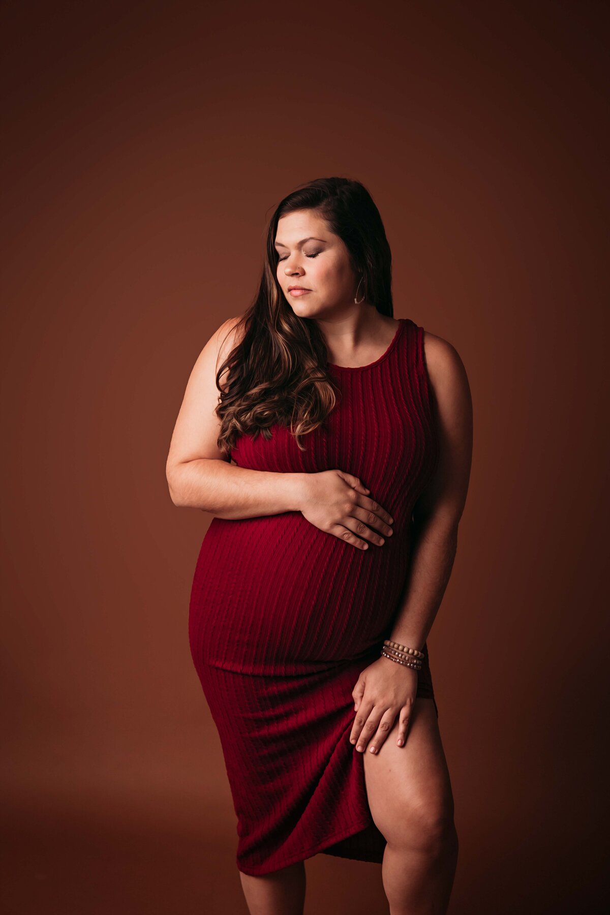 A fashionable mom-to-be in a red dress, showing a more feminine side, captured in a stylish maternity photo by a Mobile, AL Maternity photographer