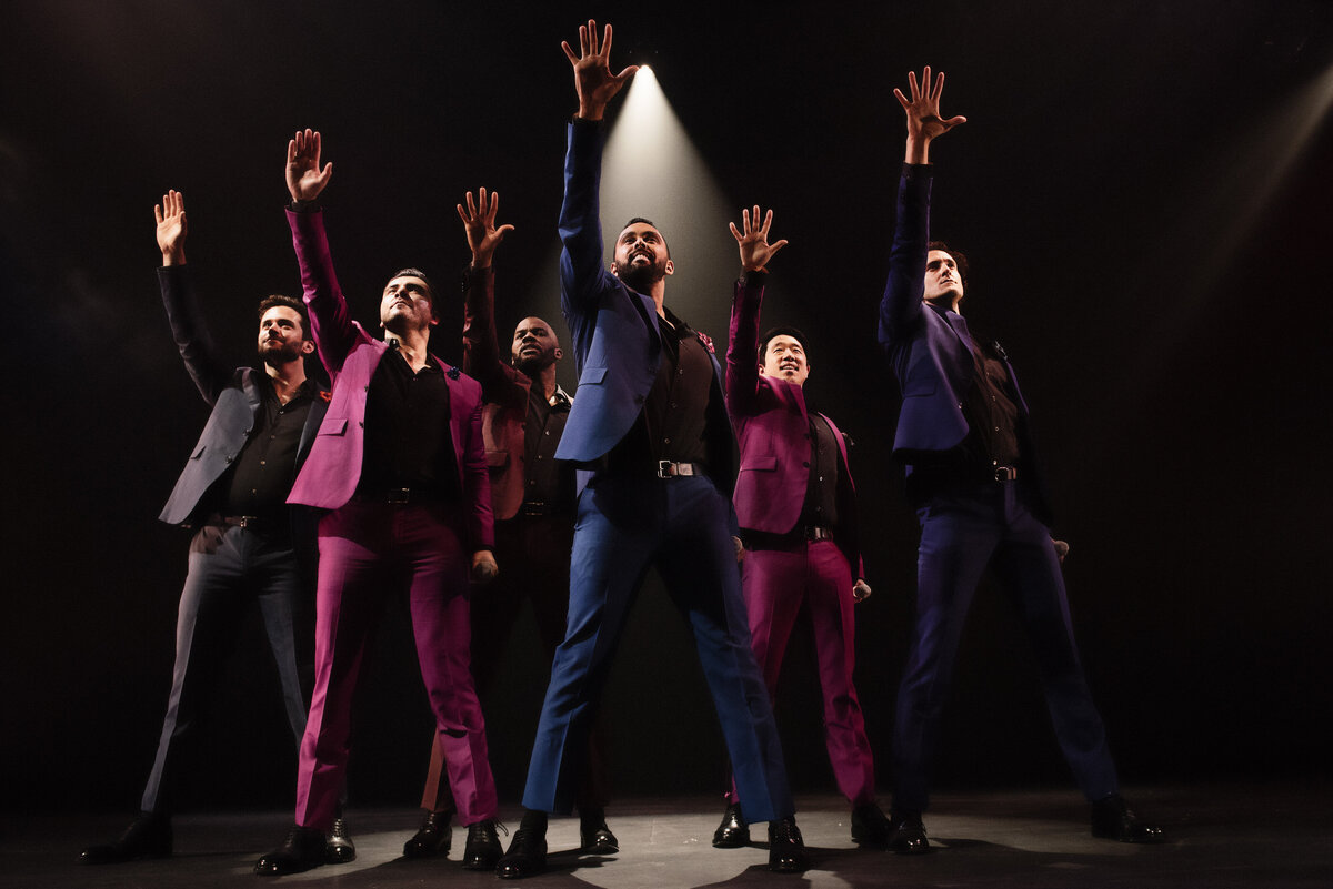 A group of men on stage reaching up