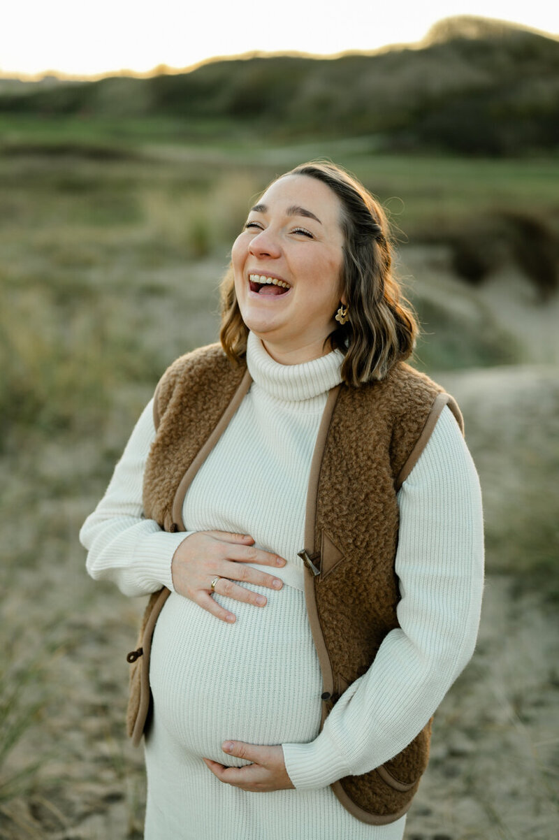 Maternity sessie in Leiden aan de kust van een zwangere, lachende vrouw.