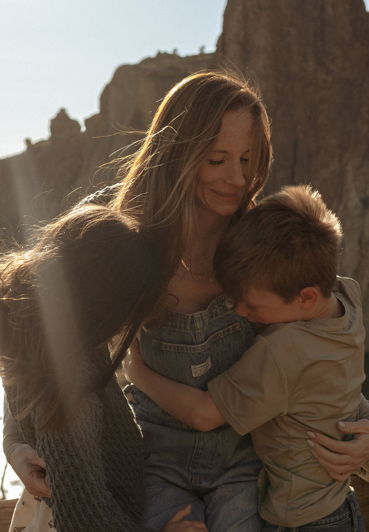 mother and two children embrace in a sweet hug during golden hour at Smith Rock
