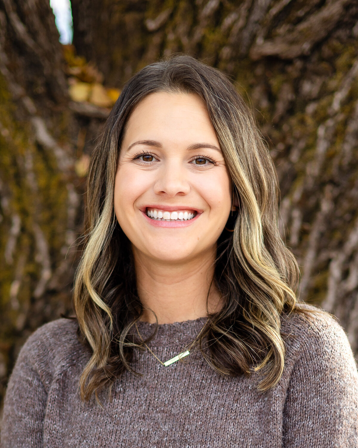 Outdoor headshot of a smiling woman for Bay Area Headshot Portfolio photographed near a tree trunk background – Ellobelle Photography