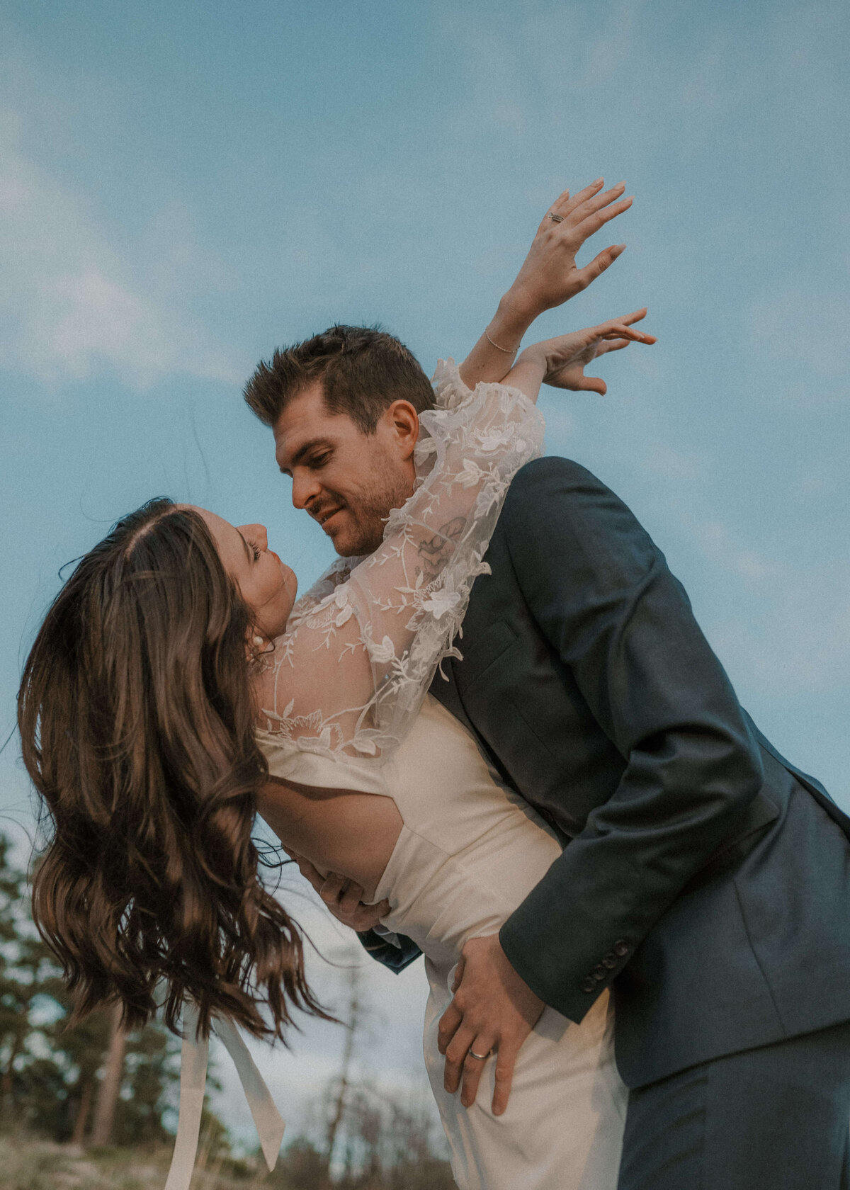 groom embracing bride and leaning over with brides arms wrapped around grooms neck on mogollon rim in payson, arizona