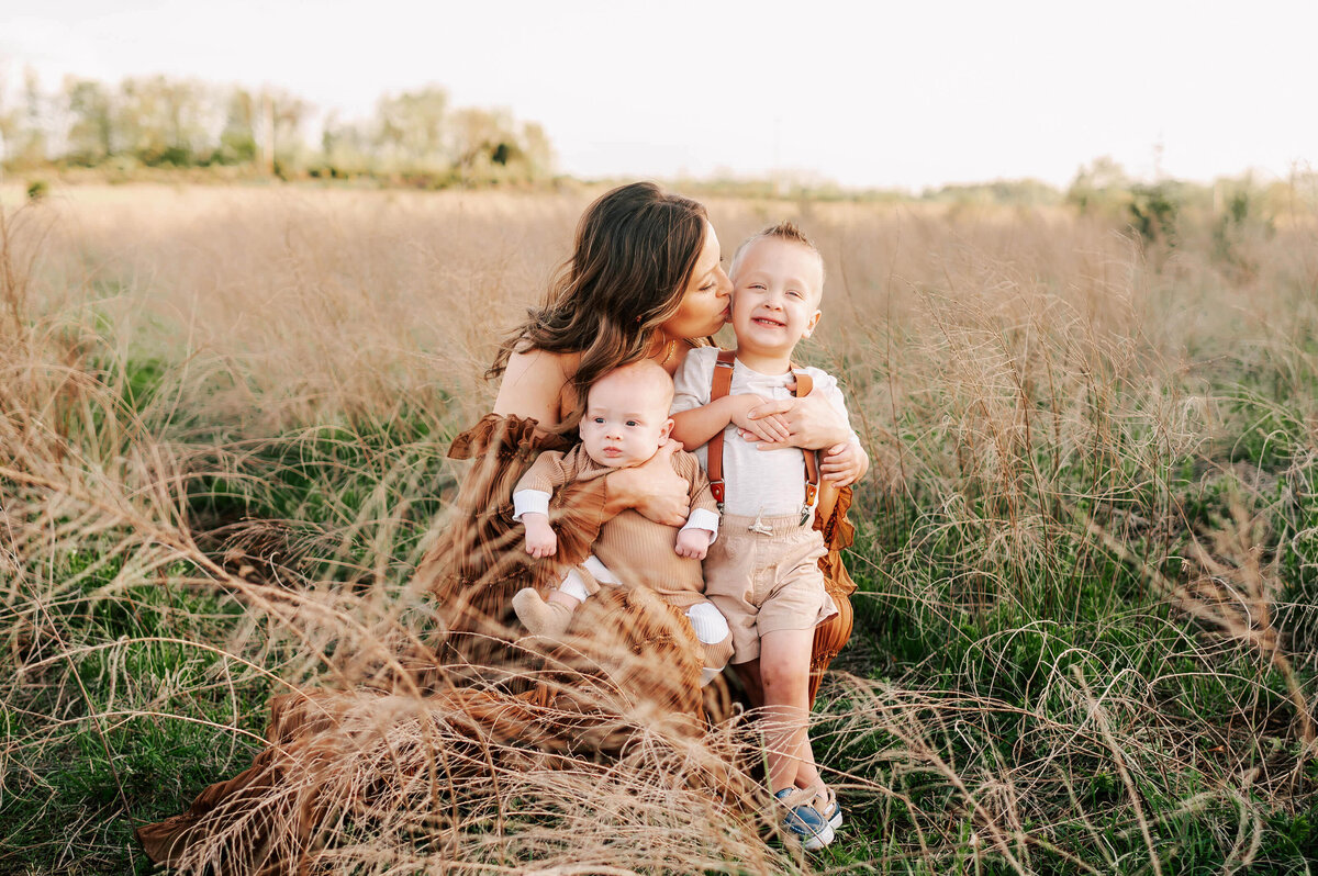 family photo in Springfield MO of mom cuddling her boys outdoors at sunset