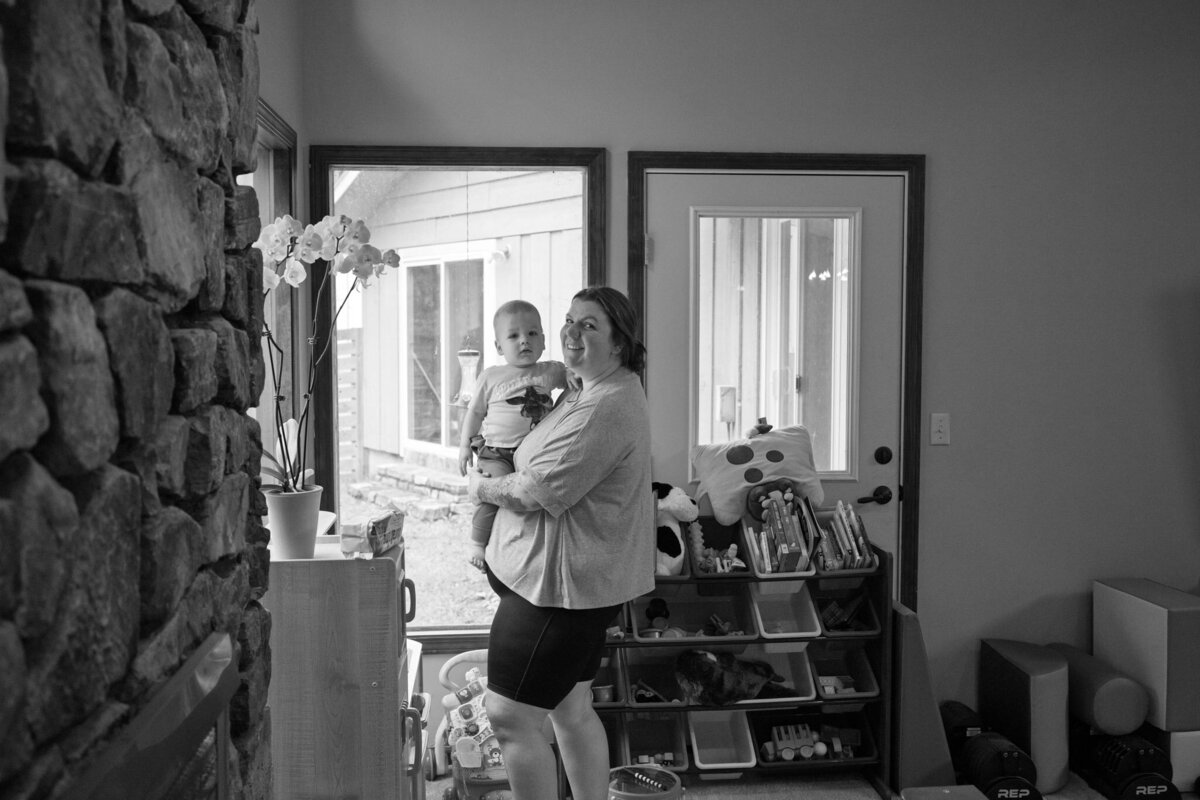 documentary photo of mother carrying toddler and smiling at the camera