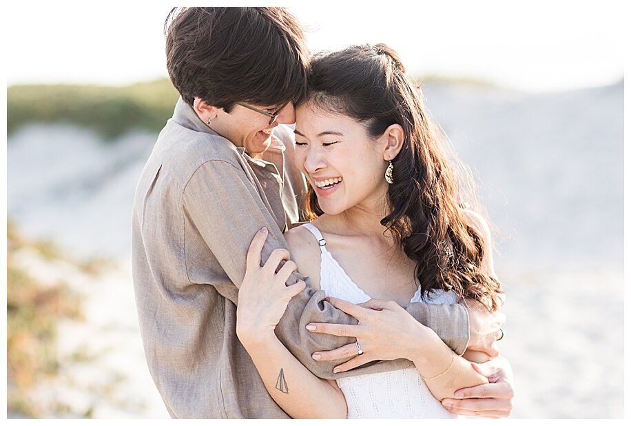engaged couple laughing and hugging in san diego sand dunes