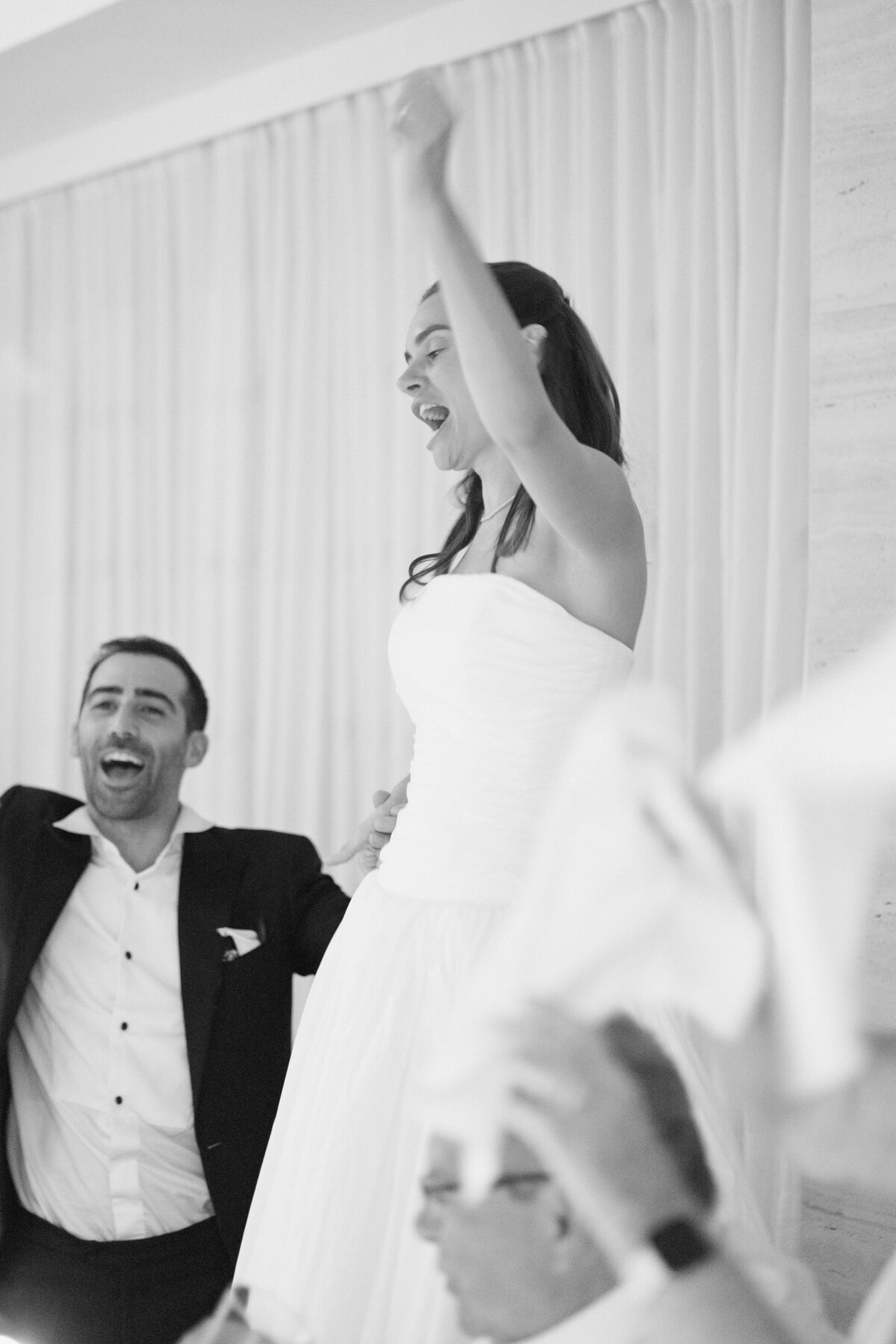 Guests raising glasses and dancing during wedding dinner celebration

