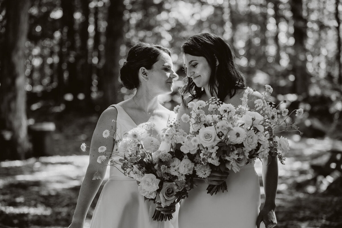 Two brides at Le Bullerie hold large bridal bouquets of lush flowers.