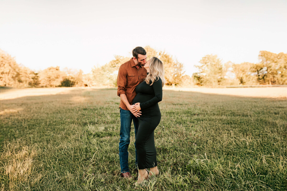 Springfield Mo maternity photographer captures pregnant mom kissing husband in field